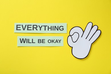 Photo of Cards with phrase Everything Will Be Okay and paper cutout of gesture on yellow background, flat lay