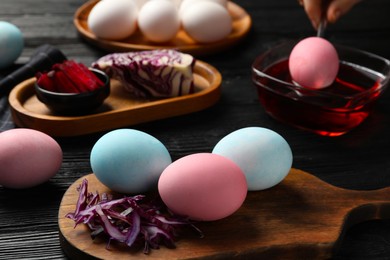 Photo of Naturally painted Easter eggs on black wooden table. Red cabbage used for coloring