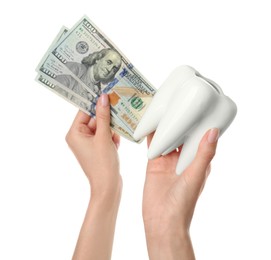 Woman holding ceramic model of tooth and dollar banknotes on white background, closeup. Expensive treatment