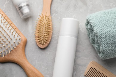 Dry shampoo sprays, towel and hairbrushes on light grey table, flat lay