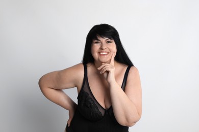 Beautiful overweight woman in black underwear on light background. Plus-size model