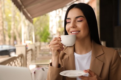 Woman with cup of aromatic coffee at outdoor cafe in morning