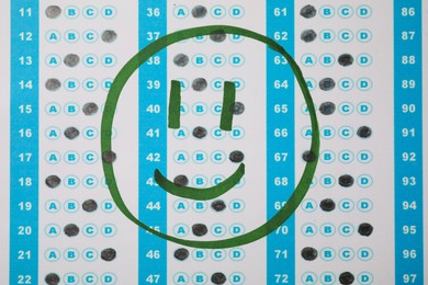 Photo of Happy face drawn on answer sheet, top view. Student passing exam