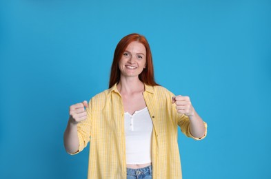 Happy young woman pretending to drive car on light blue background