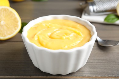 Photo of Delicious lemon curd in bowl on wooden table, closeup