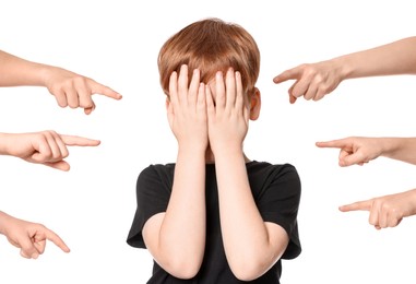 Photo of Boy covering face with hands and kids pointing at him on white background. Children's bullying