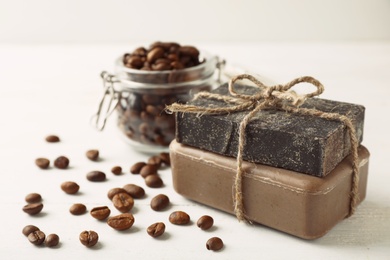 Handmade soap bars and coffee beans on white table