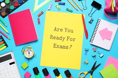 Yellow paper with question Are you ready for exams and stationery on light blue table, flat lay