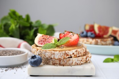 Tasty crispbreads with peanut butter, figs and berries on light table