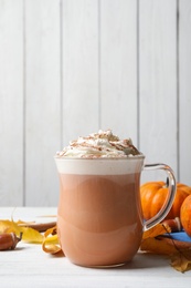 Delicious pumpkin latte with whipped cream on white table