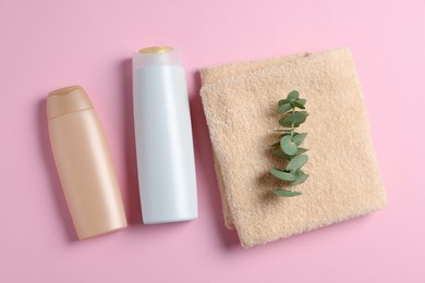 Soft folded towel with eucalyptus branch and cosmetic products on pink background, flat lay
