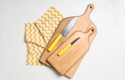 Wooden boards and knives on white background, top view. Cooking utensils
