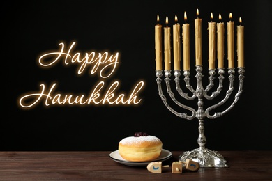 Happy Hanukkah. Silver menorah, sufganiyah and dreidels on wooden table against black background 