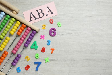 Paper sheet with abbreviation ABA (Applied behavior analysis), abacus and colorful numbers on white wooden table, flat lay. Space for text