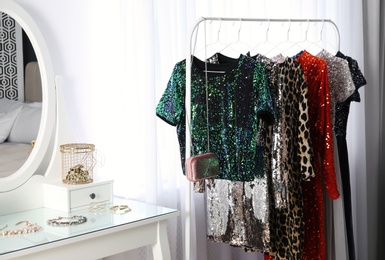 Rack with collection of beautiful festive clothes and dressing table in stylish room interior