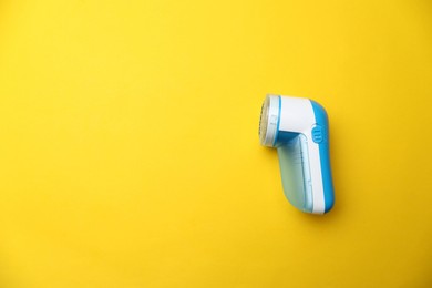 Photo of Modern fabric shaver on yellow background, top view. Space for text