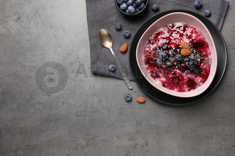 Tasty oatmeal porridge with toppings on grey table, flat lay. Space for text