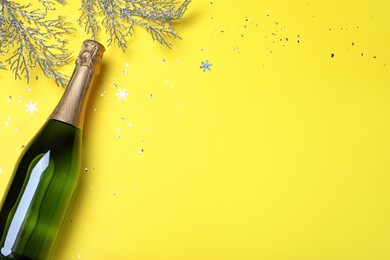 Happy New Year! Flat lay composition with bottle of sparkling wine on yellow background, space or text