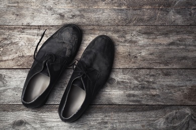 Dirty shoes and space for text on wooden background, top view. Poverty concept