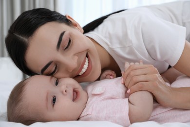Young mother with her little baby on bed at home