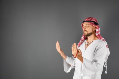 Muslim man praying on gray background. Space for text
