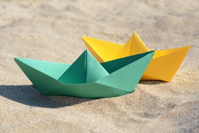 Photo of Two color paper boats on sandy beach, closeup