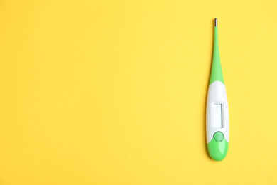 Modern digital thermometer on yellow background, top view. Space for text