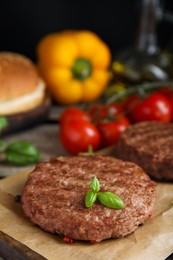 Tasty grilled hamburger patties with basil served on table, closeup