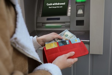 Image of Woman putting money into wallet near cash machine outdoors, closeup