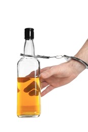 Addicted man in handcuffs with bottle of alcoholic drink on white background, closeup