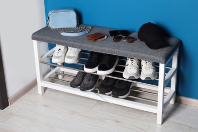 Photo of Shoe storage bench with accessories near blue wall in hallway. Interior design