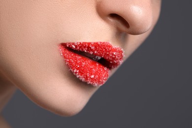 Woman with beautiful lips covered in sugar on grey background, closeup