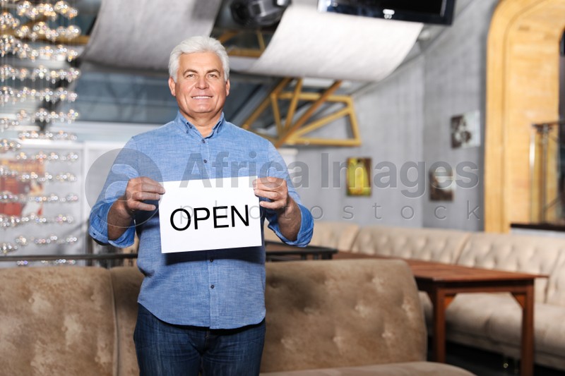 Senior business owner holding OPEN sign in his restaurant