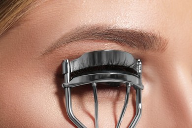Young woman using eyelash curler, closeup view