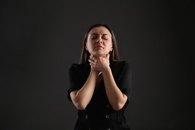 Photo of Portrait of young woman choking her neck on black background. Personality concept