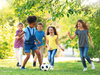 Image of School holidays. Group of happy children playing football outdoors 