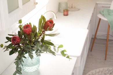 Photo of Bouquet with beautiful protea flowers on countertop in kitchen, space for text. Interior design