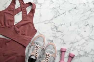 Flat lay composition with sportswear and equipment on white marble table, space for text. Gym workout