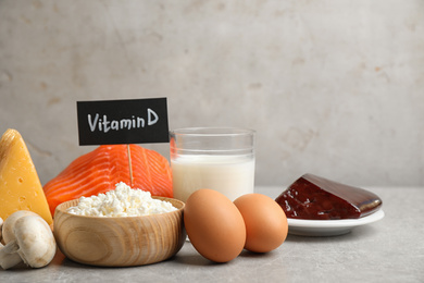 Photo of Paper with phrase VITAMIN D and fresh products on light table