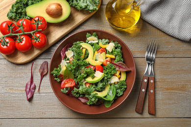 Tasty fresh kale salad on wooden table, flat lay