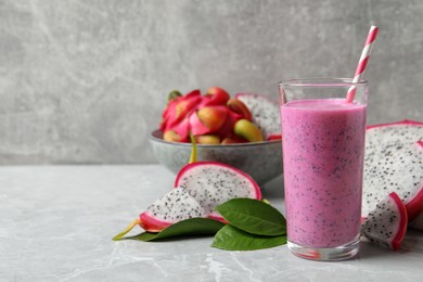 Glass of tasty pitahaya smoothie and fresh fruits on light grey table, space for text