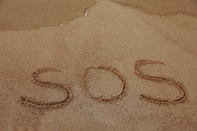 Message SOS drawn on sandy beach, space for text