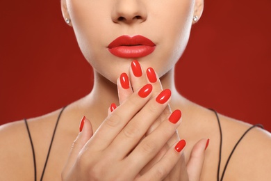 Beautiful young woman with bright manicure on color background, closeup. Nail polish trends