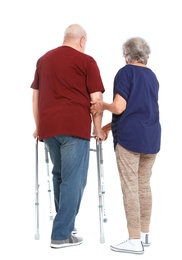 Elderly woman helping her husband with walking frame on white background