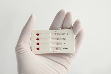 Doctor holding disposable express test for hepatitis on white background, closeup