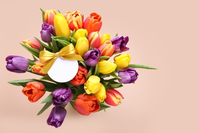 Photo of Bouquet of beautiful colorful tulips with blank card on beige background, top view and space for text. Birthday celebration