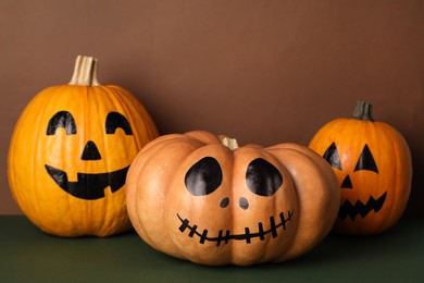 Pumpkins with drawn spooky faces on color background. Halloween celebration