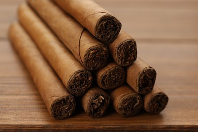 Many cigars on wooden table, closeup. Tobacco smoking