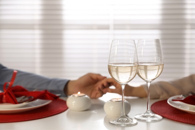 Couple having romantic dinner at home, focus on glasses of wine