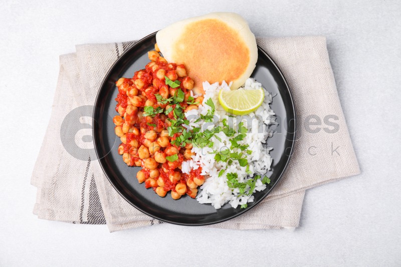 Delicious chickpea curry with rice and flatbread on light gray table, flat lay